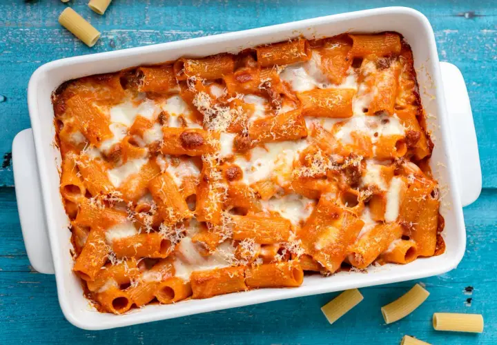 Un invitante piatto di pasta al forno, con rigatoni conditi con sugo rosso e abbondante formaggio fuso, pronto per essere gustato.