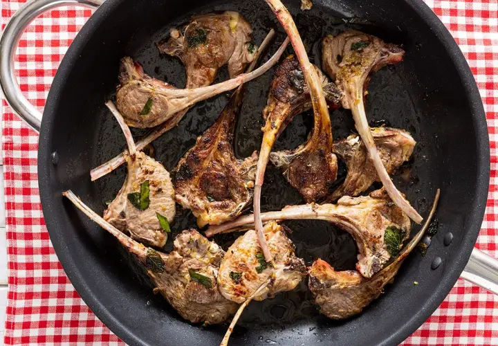 Costine di agnello in padella, dorate e succulente, pronte per essere gustate.