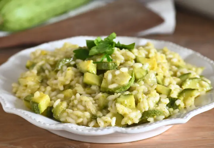 Un cremoso risotto con zucchine, guarnito con prezzemolo fresco, pronto per essere gustato.