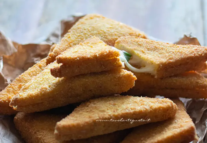 Mozzarella in carrozza dorate e croccanti, con il formaggio filante che fuoriesce da una fetta.