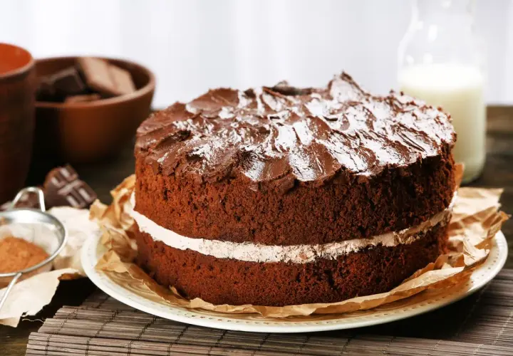 Torta al cioccolato a due strati, con glassa e zucchero a velo, che ricorda una torta Kinder Delice fatta in casa.