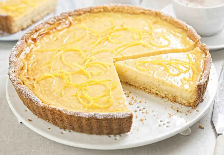 Una deliziosa crostata con crema pasticcera, guarnita con scorza di limone e spolverata di zucchero a velo. Perfetta per ogni occasione.