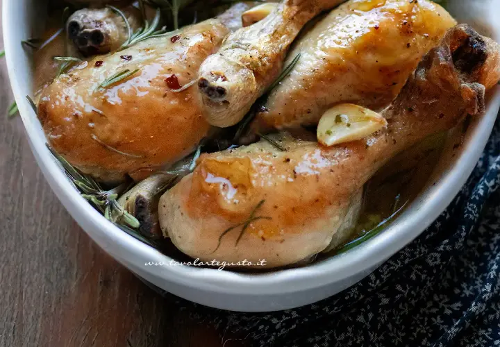 Succulenti fusi di pollo al forno, dorati e profumati con aglio e rosmarino, serviti in una ciotola bianca.