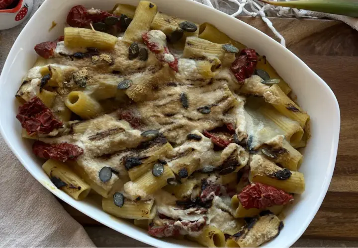 Piatto di pasta con carciofi alla siciliana, pomodori secchi e semi di zucca, gratinata al forno.