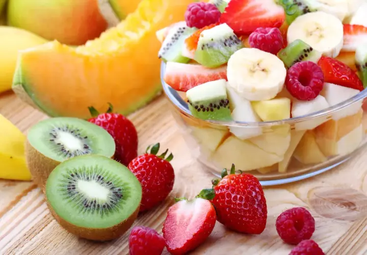 Una fresca macedonia di frutta, con fragole, kiwi, banane e melone, pronta per essere gustata.