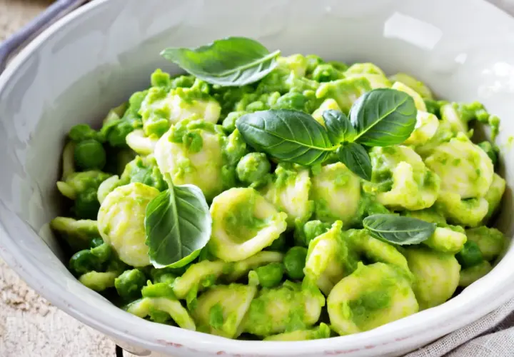 Orecchiette fatte in casa con crema di piselli e basilico fresco, un piatto primaverile invitante.