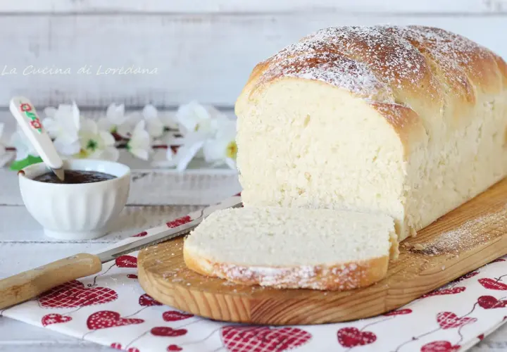 Un soffice pan brioche dolce, spolverato di zucchero a velo, pronto per essere gustato con marmellata.