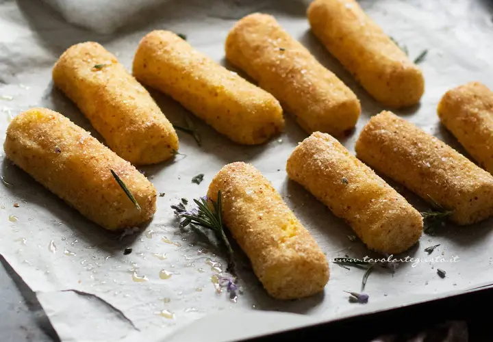 Crocchette di patate al forno dorate e croccanti, pronte per essere gustate. Profumano di rosmarino e sale grosso.