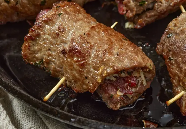 Involtini di carne in padella con sughetto, ripieni e cotti a puntino, pronti per essere gustati.