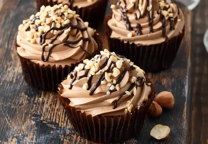 Cupcake con soffice crema di nocciole, decorato con cioccolato fuso e granella di nocciole tostate.