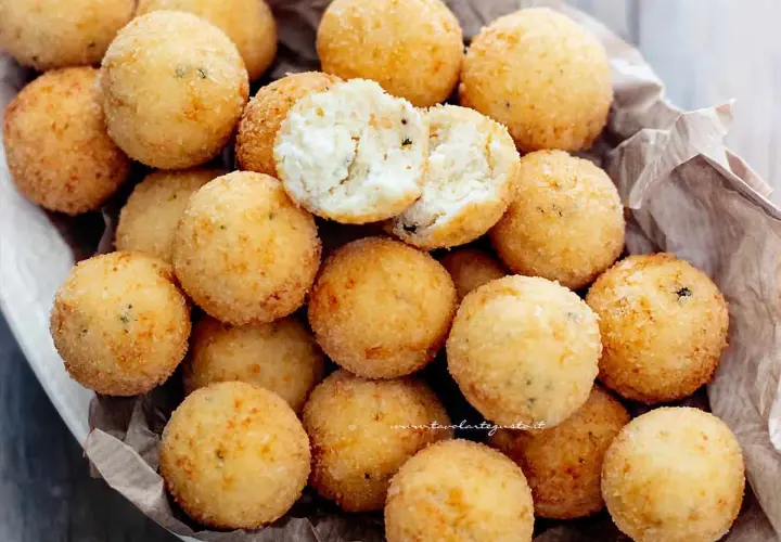 Un cesto pieno di croccanti polpette di ricotta, dorate e invitanti. Una è aperta, mostrando il morbido interno.