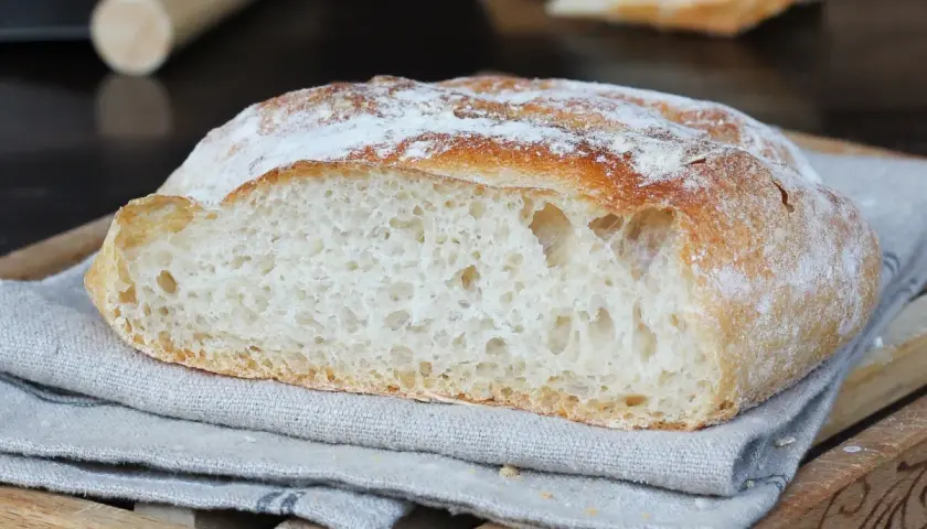 Pane fatto in casa, con crosta dorata e mollica alveolata, adagiato su un tovagliolo di lino.
