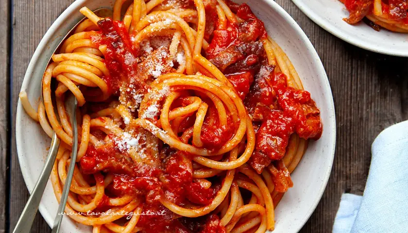 Un piatto fumante di bucatini all'amatriciana ricetta originale, conditi con guanciale croccante e pomodoro.