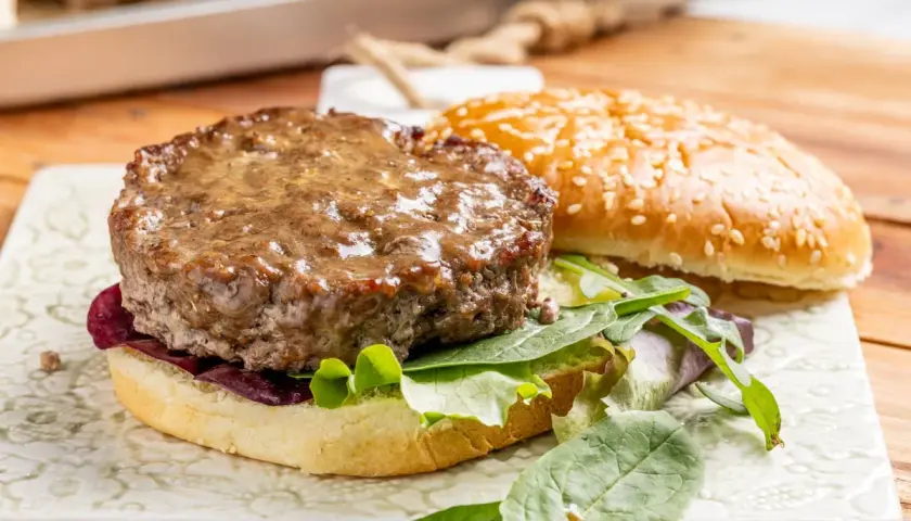Hamburger al forno succulento su pane con sesamo, insalata fresca e cipolla rossa.