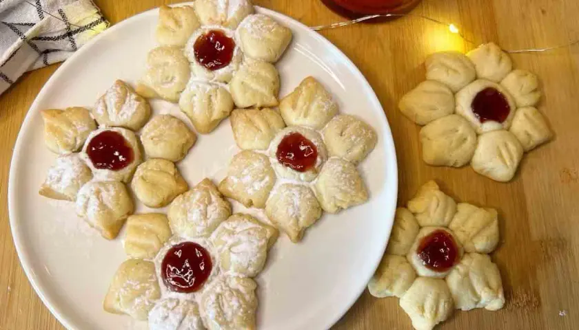 Deliziosi biscotti con marmellata a forma di fiore, spolverati di zucchero a velo, pronti per essere gustati.