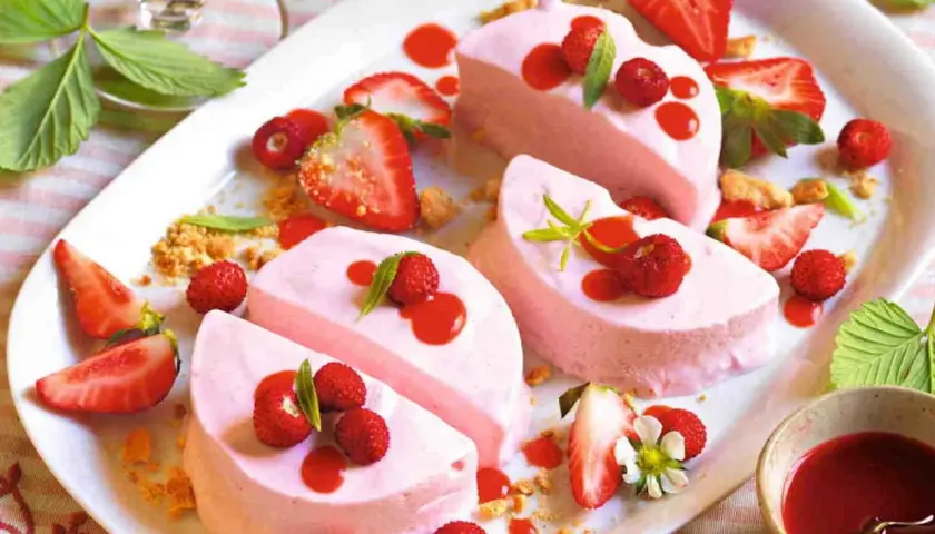 Delizioso semifreddo alle fragole, guarnito con fragoline di bosco, salsa rossa e foglioline verdi. Un dolce estivo perfetto.