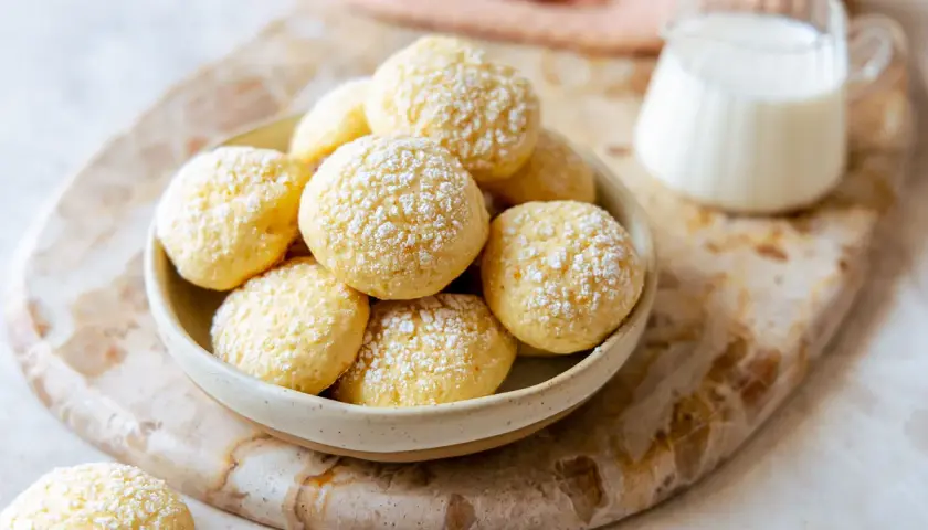 Biscotti da inzuppo soffici e dorati, cosparsi di zucchero a velo, pronti per essere gustati con un bicchiere di latte.