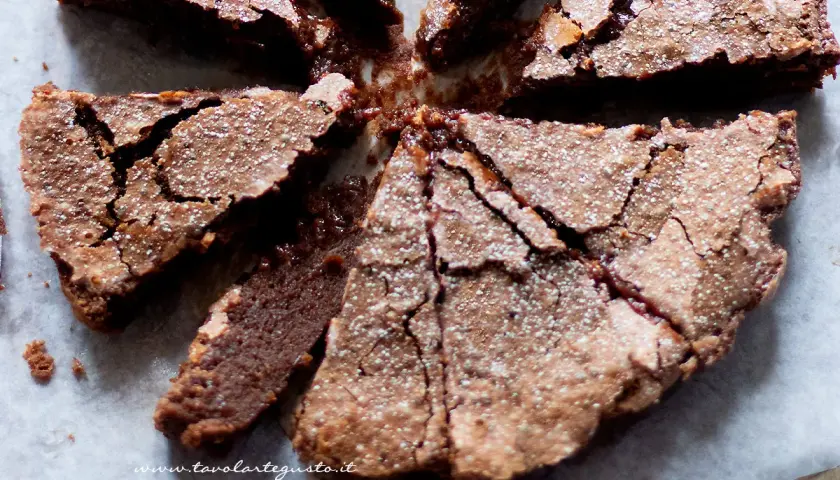 Torta morbida al cioccolato, tagliata a spicchi, cosparsa di zucchero a velo, perfetta per celebrare la Pasqua con un tocco goloso.