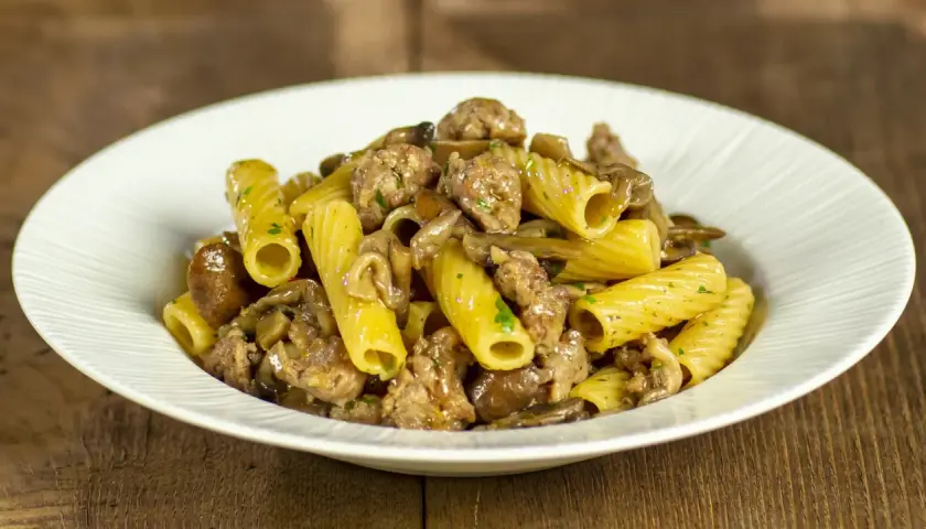 Piatto di pasta con funghi e salsiccia, un classico saporito.