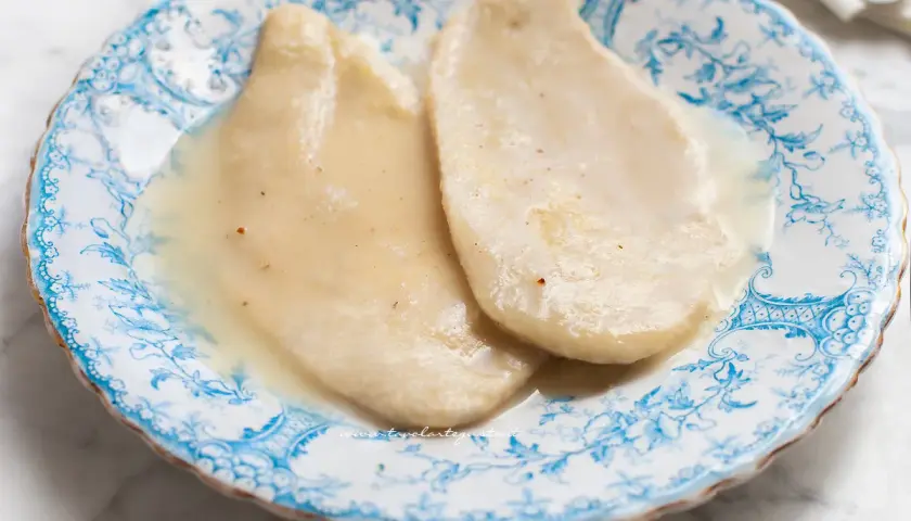 Due scaloppine al vino bianco, tenere e succulente, servite su un piatto di ceramica decorato con motivi blu.