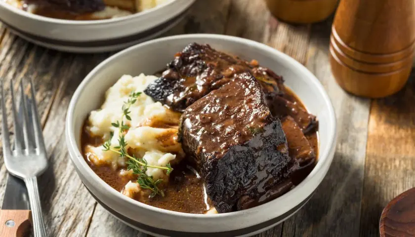 Un succulento brasato di manzo servito con purè di patate e guarnito con timo fresco.