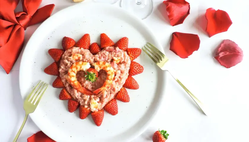 Un cuore di risotto alle fragole, decorato con gamberi e fragole fresche, pronto per un'occasione speciale.