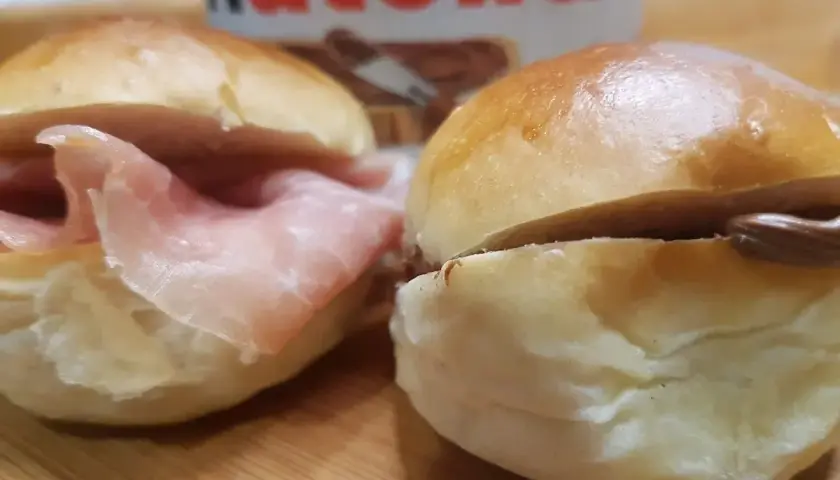 Due panini al latte, uno con prosciutto e l'altro con Nutella, pronti per essere gustati.