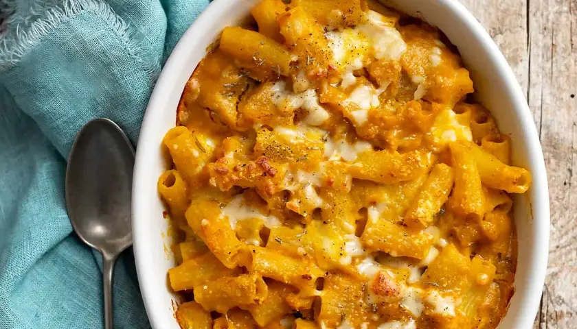 Piatto invitante di pasta con la zucca, gratinata al forno con formaggio filante e erbe aromatiche.