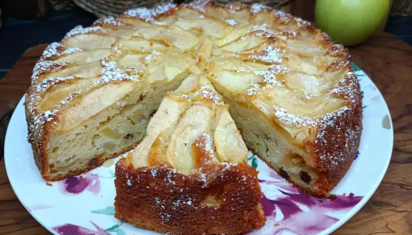 Una fetta di torta di mele soffice e profumata, cosparsa di zucchero a velo, pronta per essere gustata.