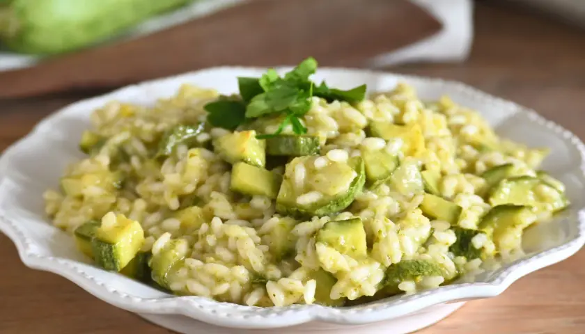 Un cremoso risotto con zucchine, guarnito con prezzemolo fresco, pronto per essere gustato.