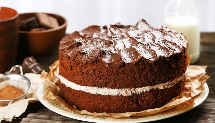 Torta al cioccolato a due strati, con glassa e zucchero a velo, che ricorda una torta Kinder Delice fatta in casa.