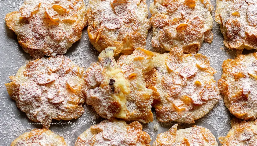 Biscotti croccanti, simili a rose del deserto, ricoperti di zucchero a velo e fiocchi di mais.