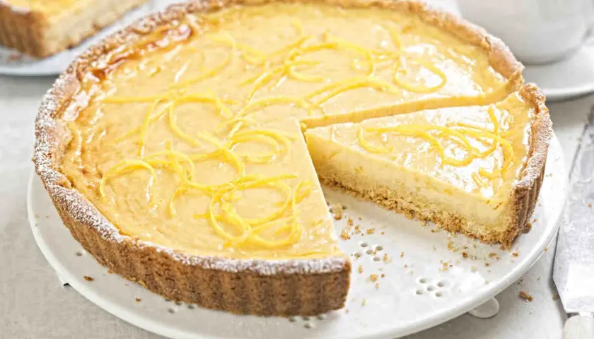 Una deliziosa crostata con crema pasticcera, guarnita con scorza di limone e spolverata di zucchero a velo. Perfetta per ogni occasione.