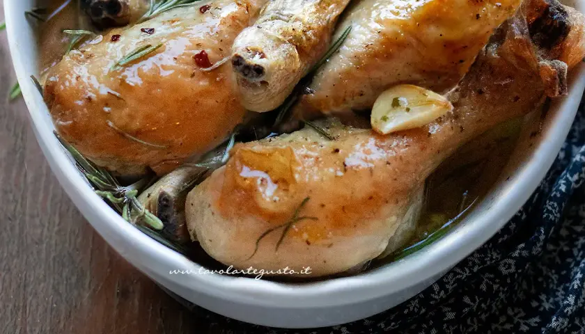 Succulenti fusi di pollo al forno, dorati e profumati con aglio e rosmarino, serviti in una ciotola bianca.