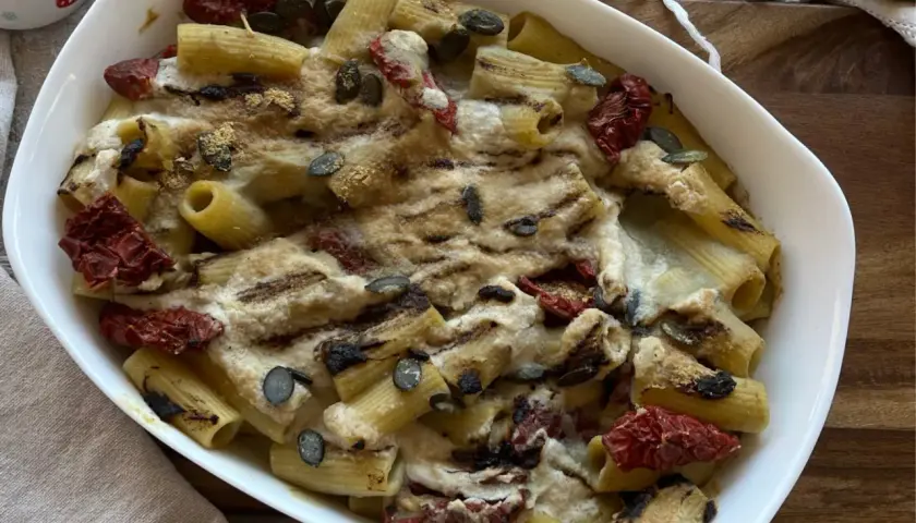 Piatto di pasta con carciofi alla siciliana, pomodori secchi e semi di zucca, gratinata al forno.