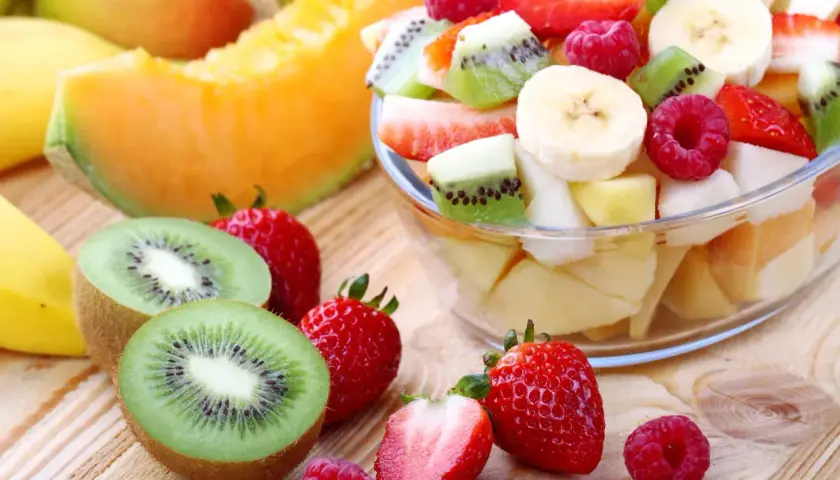 Una fresca macedonia di frutta, con fragole, kiwi, banane e melone, pronta per essere gustata.