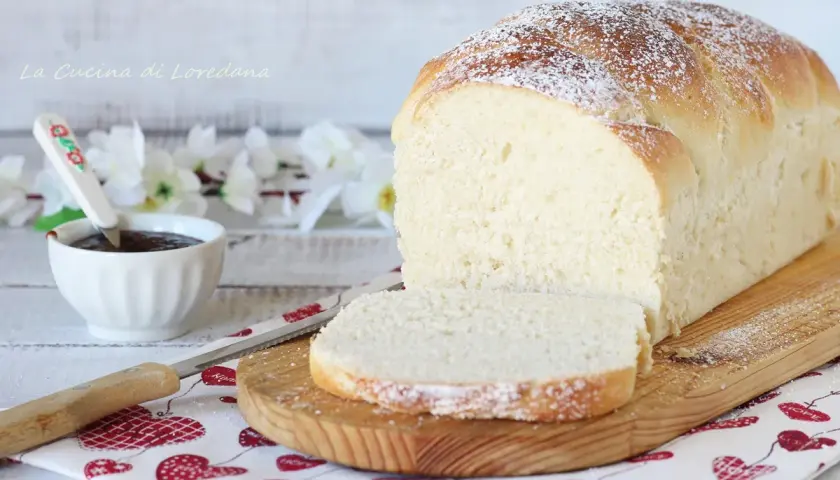 Un soffice pan brioche dolce, spolverato di zucchero a velo, pronto per essere gustato con marmellata.