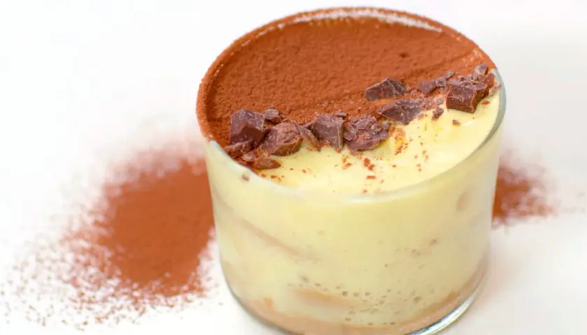 Un bicchiere di tiramisù, con cacao e scaglie di cioccolato. Perfetto per scoprire come si fa il tiramisù.