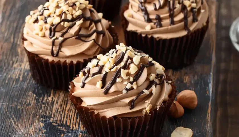 Cupcake con soffice crema di nocciole, decorato con cioccolato fuso e granella di nocciole tostate.