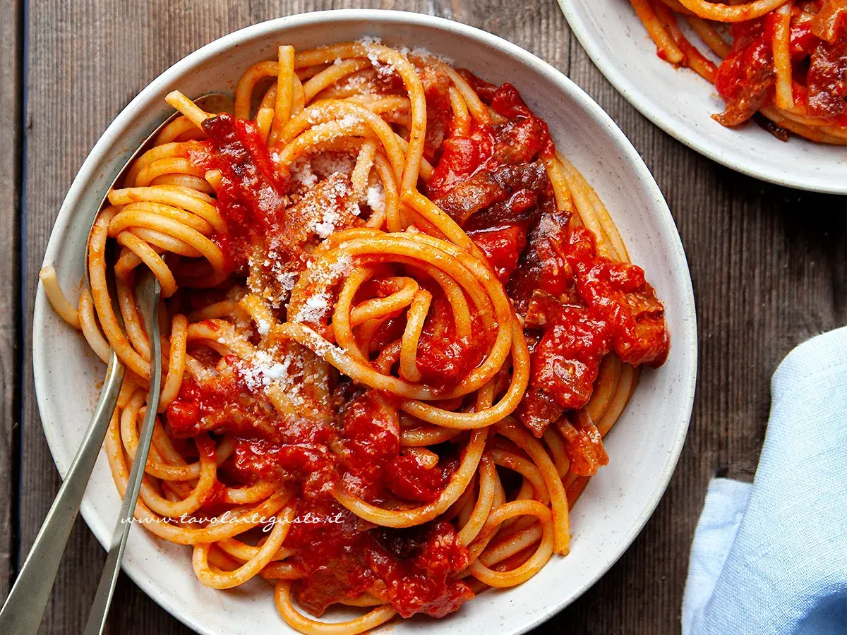 Un piatto fumante di bucatini all'amatriciana ricetta originale, conditi con guanciale croccante e pomodoro.