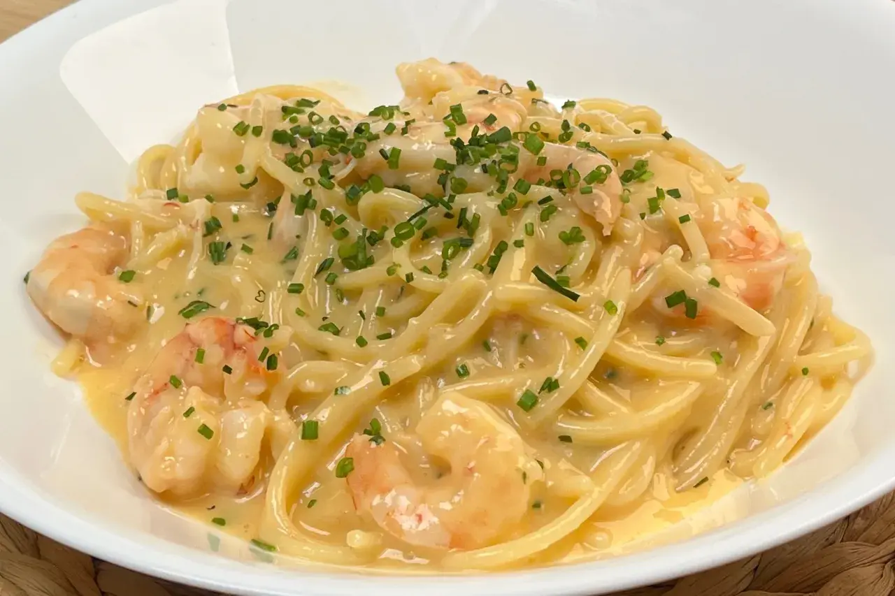 Spaghetti cremosi con gamberi e una spolverata di erba cipollina, un'invitante carbonara di mare.