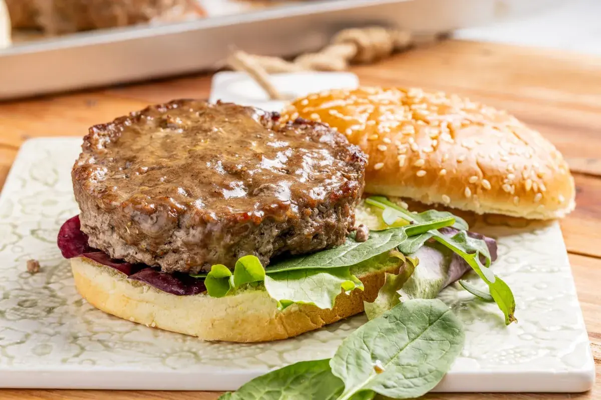 Hamburger al forno succulento su pane con sesamo, insalata fresca e cipolla rossa.