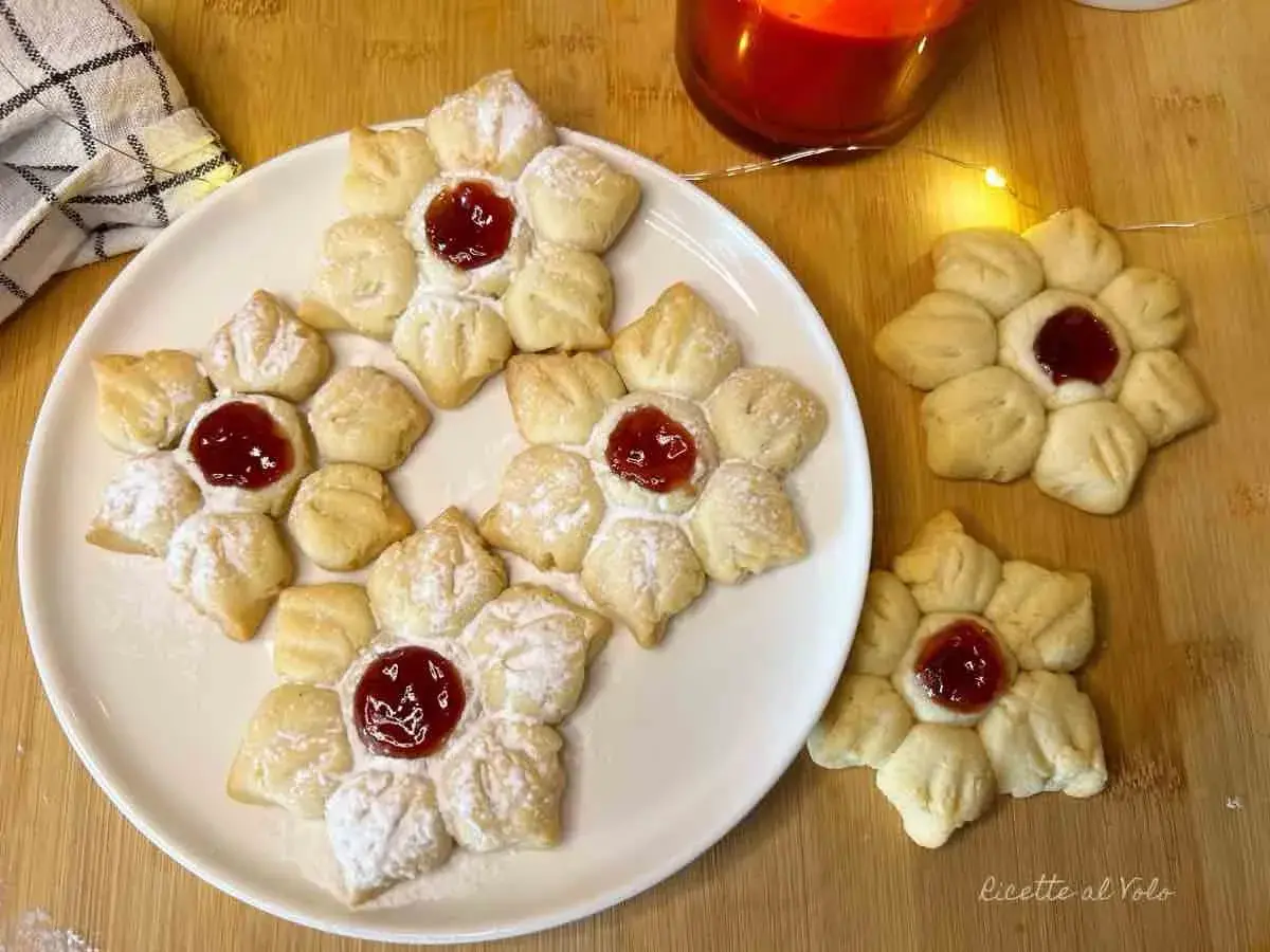 Deliziosi biscotti con marmellata a forma di fiore, spolverati di zucchero a velo, pronti per essere gustati.