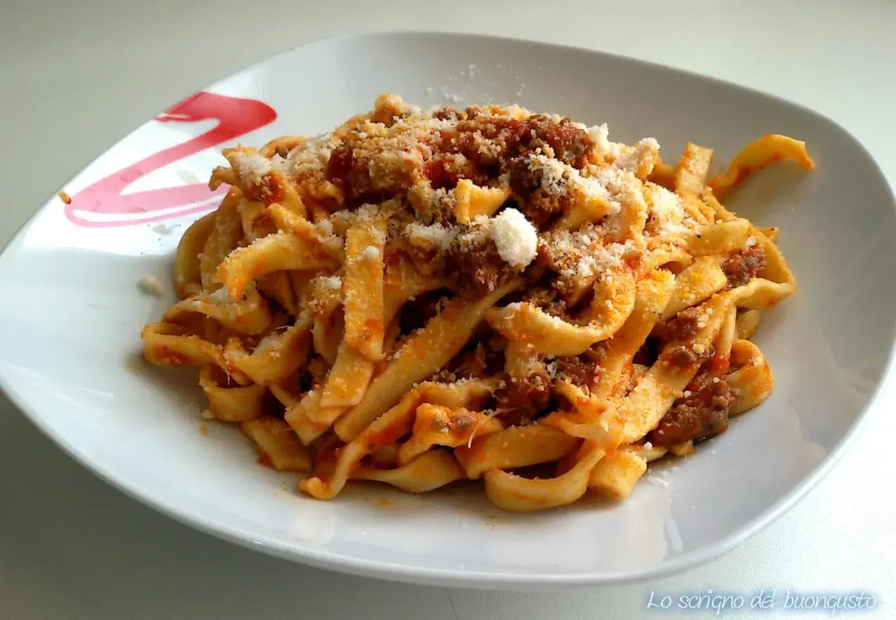 Un piatto di tagliatelle al ragù fumanti, condite con abbondante parmigiano grattugiato. Un classico della cucina italiana.