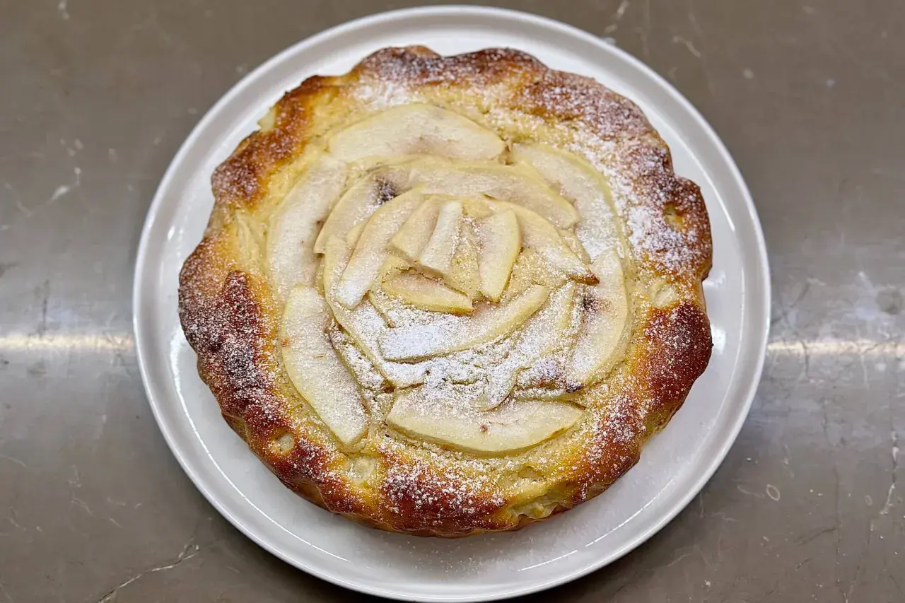Torta ricotta e pere dorata, con fette di pera disposte a raggiera e spolverata di zucchero a velo.