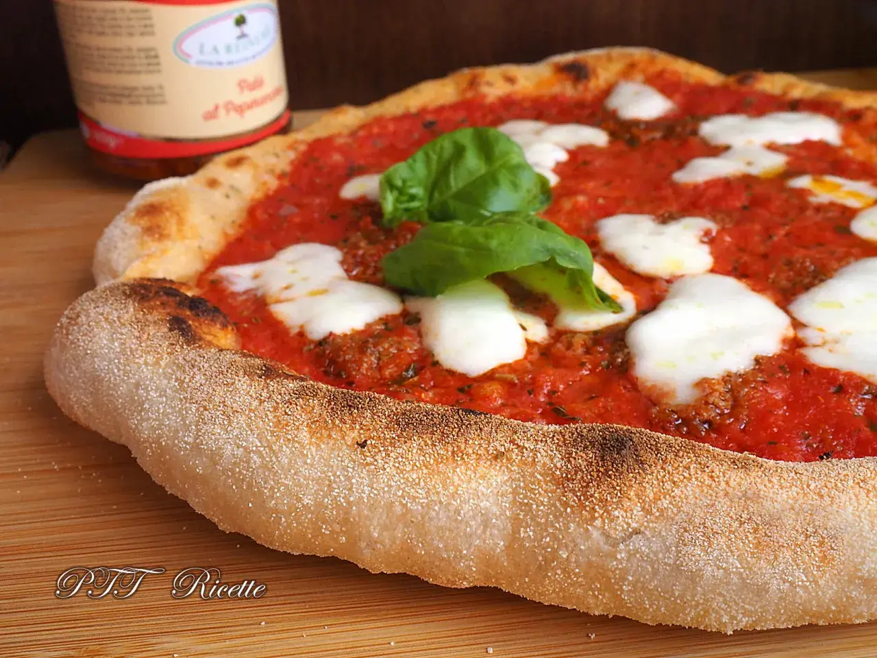 Pizza margherita con pomodoro, mozzarella filante e basilico fresco. La crosta dorata e alveolata è il risultato di una lunga lievitazione.