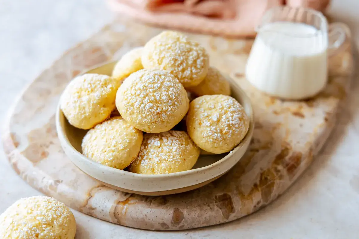 Biscotti da inzuppo soffici e dorati, cosparsi di zucchero a velo, pronti per essere gustati con un bicchiere di latte.