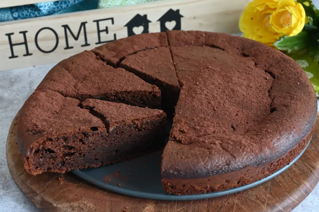 Un invitante dolce al cioccolato, cosparso di cacao, pronto per essere gustato. Sullo sfondo, una decorazione con la parola "HOME" e fiori gialli.