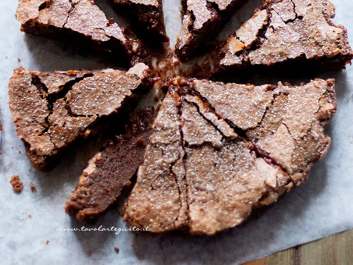 Torta morbida al cioccolato, tagliata a spicchi, cosparsa di zucchero a velo, perfetta per celebrare la Pasqua con un tocco goloso.