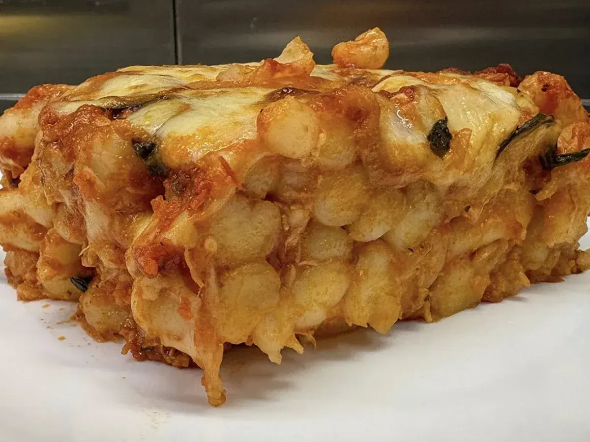 Porzione generosa di gnocchi al forno, dorati e filanti, con sugo e formaggio fuso.